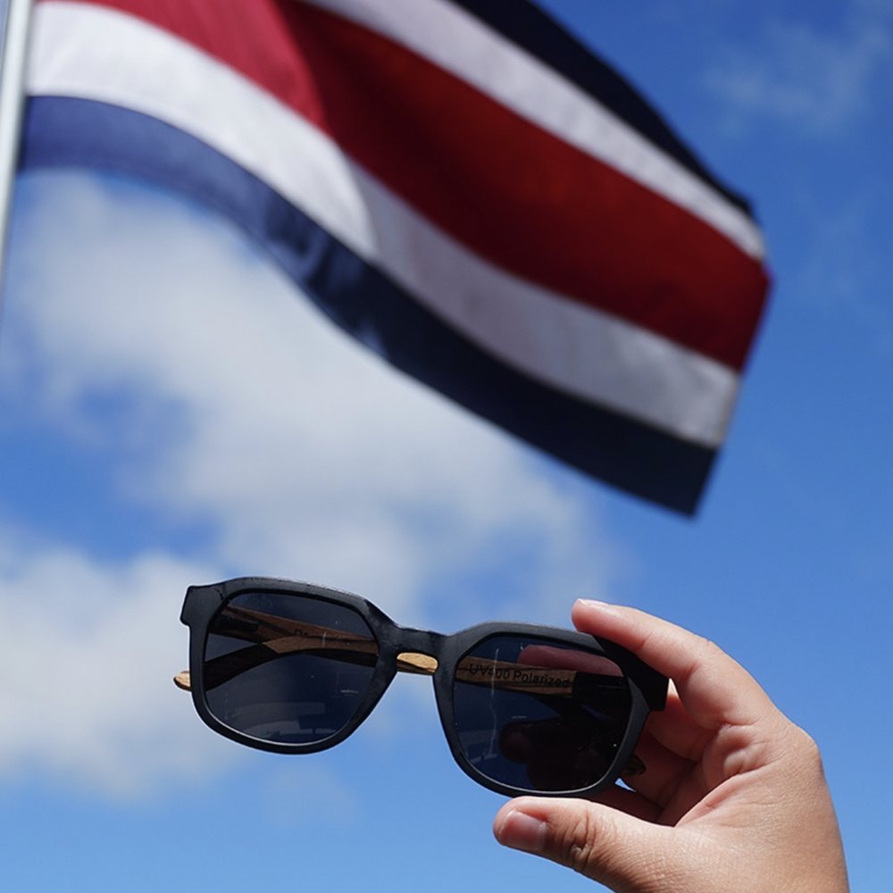 Lentes Beak con patas de madera frente a la bandera de Costa Rica