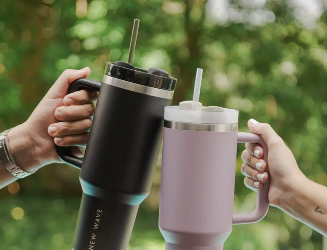 Dos personas brindando con sus Big Grip Tumbler New Wave al aire libre