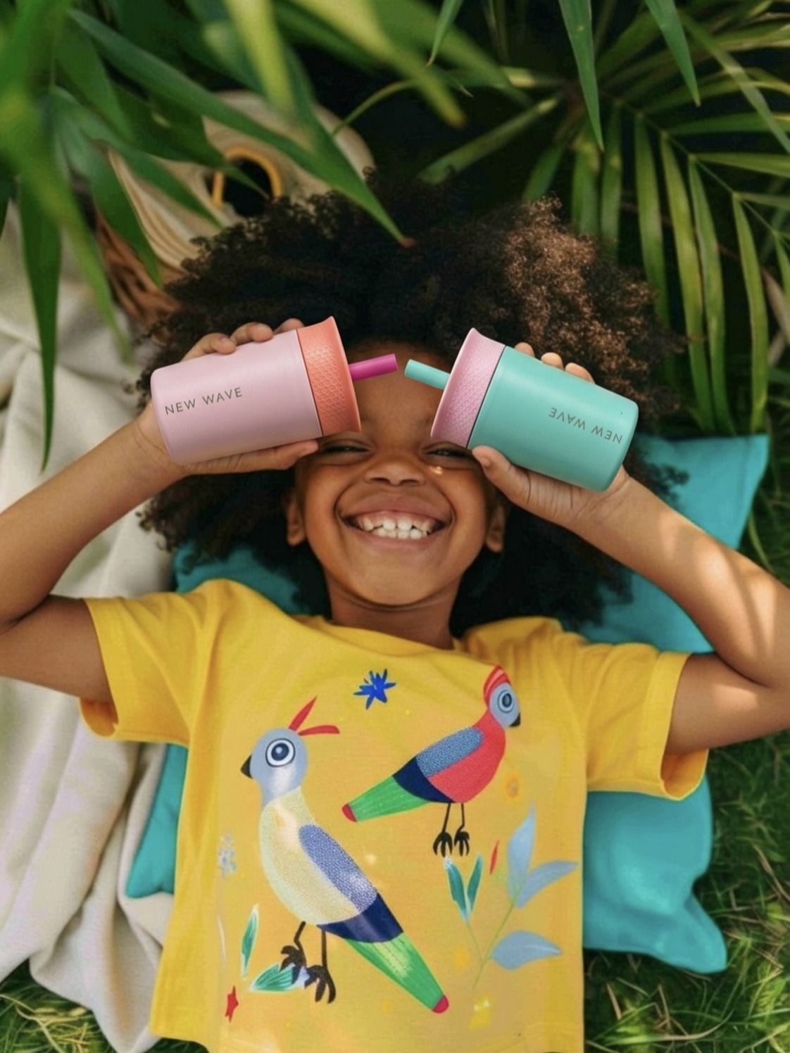 Niña sonriendo con dos vasos New Wave para peques